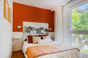 a bedroom with a bed with an orange wall at Paris West Elegant residence in Suresnes +15 photos