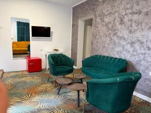 a living room with two green chairs and a couch at Pensiunea Raya in Dubova +13 photos