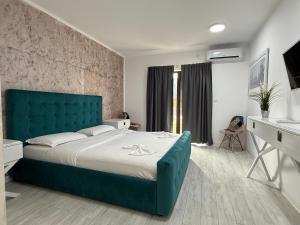 a bedroom with a large bed with a blue headboard at Pensiunea Raya in Dubova