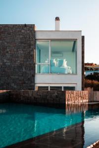 a bed in a window next to a swimming pool at Horizon Luxury Seafront Villa in Vaia +56 photos