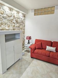 a red couch in a living room with a stone wall at Ariel Apartment Ortigia Siracusa in Siracusa