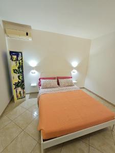 a bedroom with a bed with an orange blanket at Ariel Apartment Ortigia Siracusa in Siracusa
