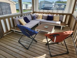 a porch with a couch and a chair on a deck at MOBILHOME camping LA FALAISE in Équihen-Plage