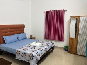 a bedroom with a bed and a red curtain at Cozy Glick in Varkala