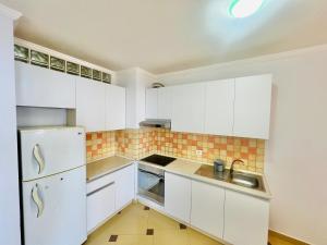 a white kitchen with white cabinets and a sink at Casa del Mar 2 in Durrës +21 photos