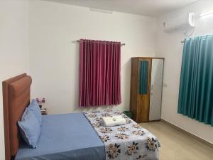 a bedroom with a bed and two windows with curtains at Cozy Glick in Varkala