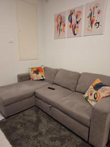 ein braunes Sofa in einem Wohnzimmer mit Gemälden an der Wand in der Unterkunft Valle Cinque in Fano