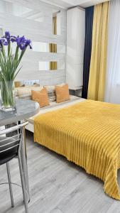 a bedroom with a bed and a table with purple flowers at Apartment Studio New York 51 in Irpin'