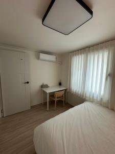 a bedroom with a bed and a table and a window at A peaceful rest stop on your journey in Busan