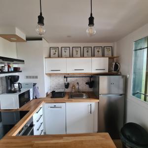 a kitchen with white cabinets and a stainless steel refrigerator at Duplex au cœur du bourg à 10 minutes de la plage in Biscarrosse