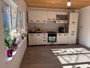 a kitchen with white cabinets and a large window at Casa Dumitru in 2 Mai