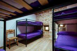 two bunk beds in a room with purple sheets at L'alberg la rectoria de la Torra in La Baronia de Rialb