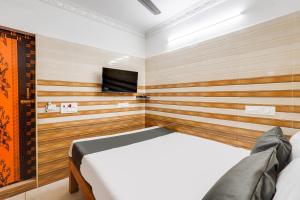 a bedroom with a bed and a flat screen tv at Super Hotel O Sharmila Guest House in Puducherry +21 photos
