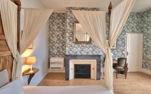 a bedroom with a fireplace and a bed with curtains at Demeures & Château - Fleur de Roques - Puisseguin Saint Emilion in Puisseguin +38 photos