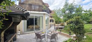 a patio with a glass table and chairs next to a house at Villa Garden - Disneyland Paris in Montévrain