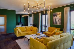 a living room with yellow furniture and green walls at Villa LM - Private Villa, Lake View, Salt Pool in Belgirate