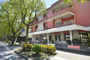 un edificio rosa con mesas blancas y sillas en una calle en Hotel Fernanda, en Cesenatico