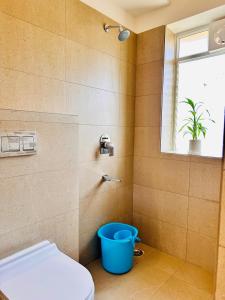 a bathroom with a toilet and a blue bucket at Kaibalya Bliss in Bhubaneshwar