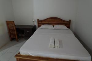 a bedroom with a bed with two towels on it at Coconut Scar Reef Homestay in Maluk