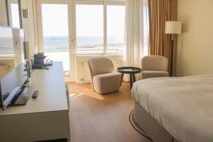 a hotel room with a bed and a view of the ocean at WestCord Hotel Schylge in West-Terschelling +72 photos