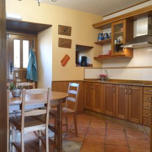 una cucina con un tavolo di legno e un tavolo e sedie di Habitaciones - La Pumarada de Limés II a Cangas del Narcea