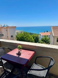 a red table and chairs on a balcony with the ocean at Cache Apartments in Ulcinj