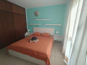 Schlafzimmer mit einem Bett mit orangefarbener Bettwäsche und blauen Wänden in der Unterkunft KALI - Apartment Tenerife Sur in Alcalá