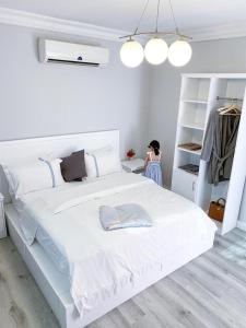 a woman standing next to a white bed in a bedroom at شقق اوبين المخدومة الدمام Open in Dammam +35 photos