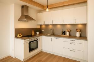 a kitchen with white cabinets and a sink at SMS-Homes I Auszeit am See #2 in Waltenhofen