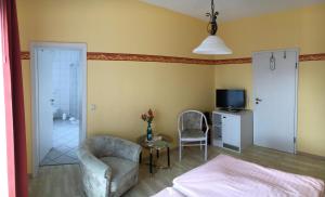 a bedroom with a bed and a chair and a tv at Kastanienhof Hotel garni in Zinnowitz +31 photos