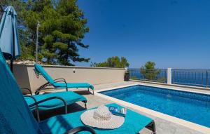 a swimming pool with chairs and a table and an umbrella at Villa Antonia by Villas Guide in Blato
