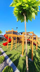 a park with a wooden playground with a tree at Kjara Apartment-Airport in Petrovec