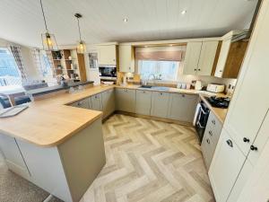 a kitchen with white cabinets and a wooden floor at The Pink Lady in Walton-on-the-Naze