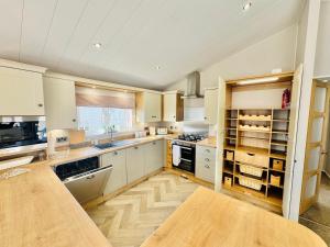 a large kitchen with white cabinets and a wooden floor at The Pink Lady in Walton-on-the-Naze