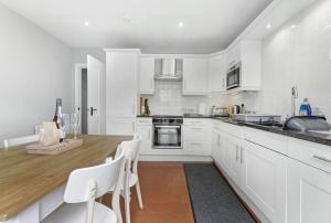 a kitchen with white cabinets and a wooden counter top at Roseberry Cottage in Ambleside +14 photos