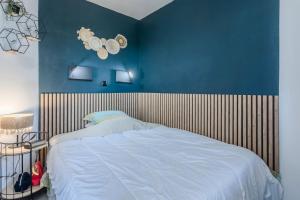 Un dormitorio con una cama con una pared azul. en Appartement Cap Esterel - piscine, en Saint-Raphaël 20 fotos más
