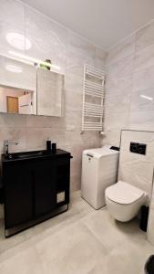 a bathroom with a white toilet and a sink at Apartament Szczęśliwy - 14 in Ustronie Morskie +21 photos