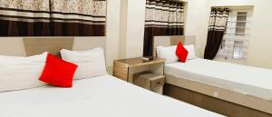 two beds with red pillows in a room at Hotel Raj DUNIYA GUEST House Kalighat WB With AC OR NON AC Room in Kolkata