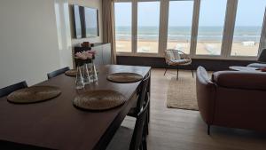 a living room with a table with a view of the beach at Valdemosa one in De Haan +23 photos