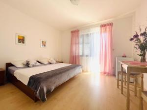 a bedroom with a bed and a window with pink curtains at Sobe-Sandra in Dramalj