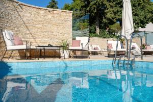 a swimming pool with chairs and a table next to a brick wall at Heritage Hotel Tisno in Tisno