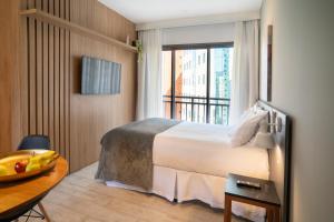 a hotel room with a bed and a table and a window at Paraíso Paulista Flats by Feel Sampa in Sao Paulo +26 photos