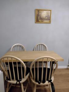 a wooden table with four chairs and a picture on the wall at Gilmerton Dykes Av in Edinburgh