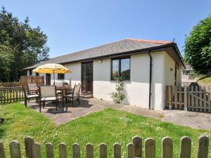 a house with a table and chairs and an umbrella at Columbine Cottage in Bude