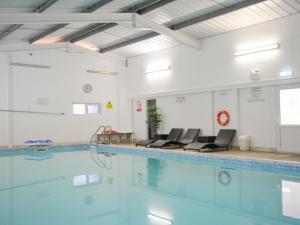 a swimming pool with blue water in a building at Columbine Cottage in Bude