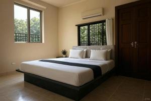 a bedroom with a large bed and two windows at Hotel Ayushman Grand in Jabalpur