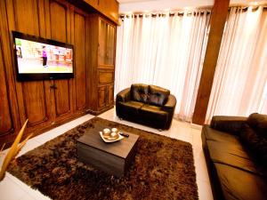 een woonkamer met 2 leren stoelen en een televisie bij Turrance White Hotel in Campinas