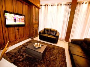 a living room with two leather chairs and a television at Turrance White Hotel in Campinas