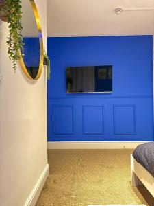 a blue wall in a bedroom with a mirror at The Coral Stay by Station in Cambridge