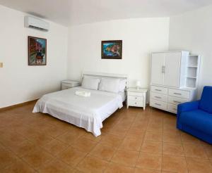 a bedroom with a white bed and a blue chair at Appartamento Albatros, Juan Dolio in Juan Dolio +7 photos